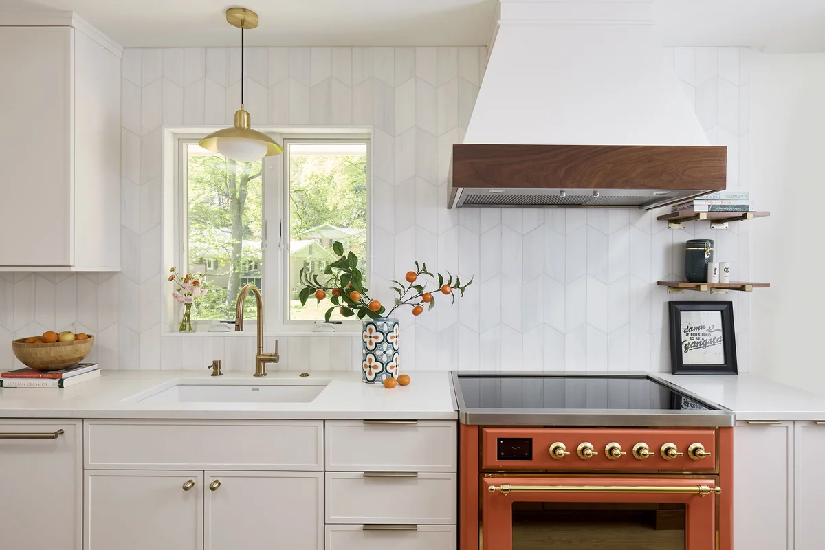 White stone countertop and sink beneath a matte marble tile backsplash beside a copper-colored range.