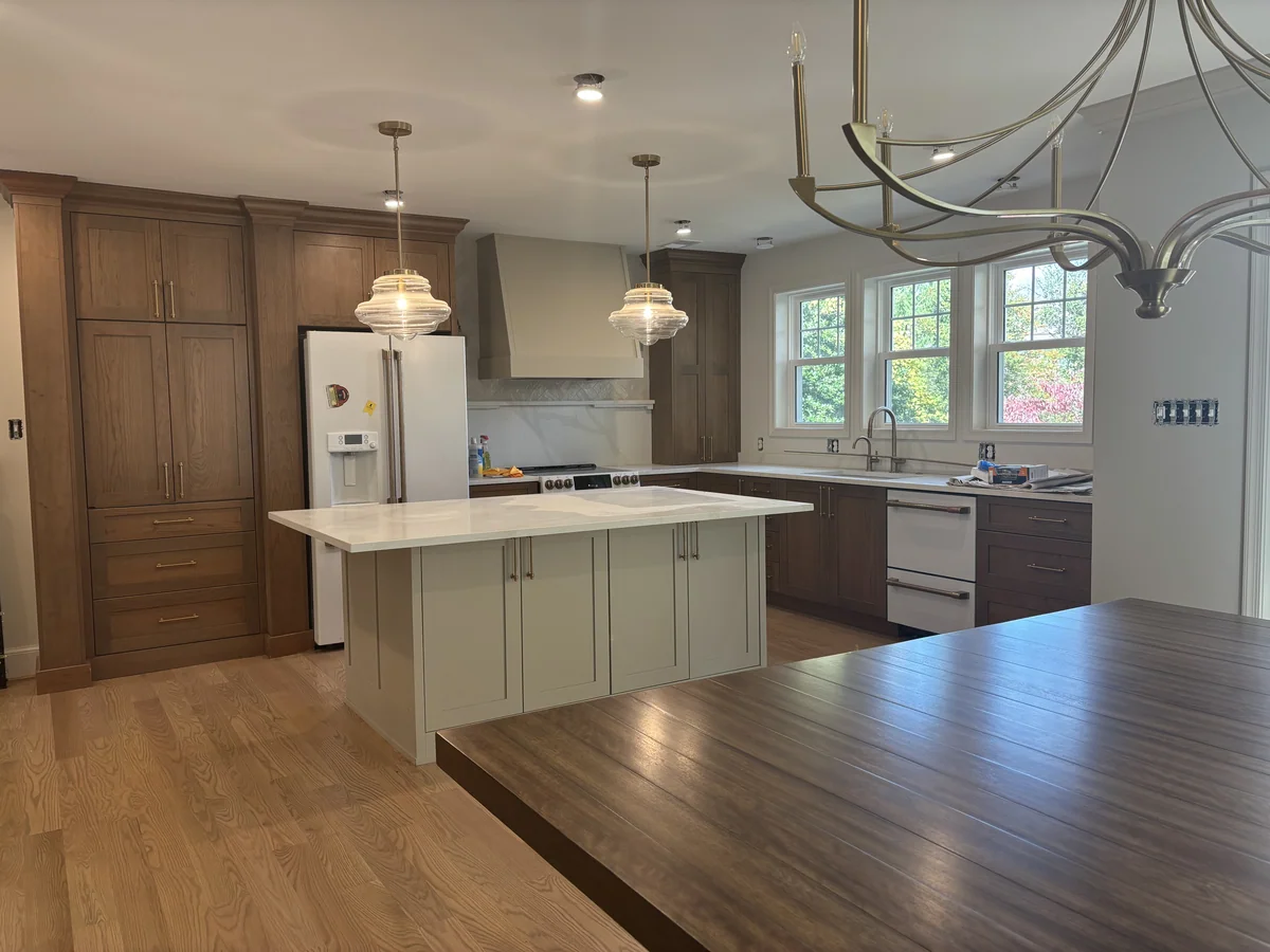 Kitchen with brown cabinetry, a custom light stone island and a projecting shelf above the backsplash.
