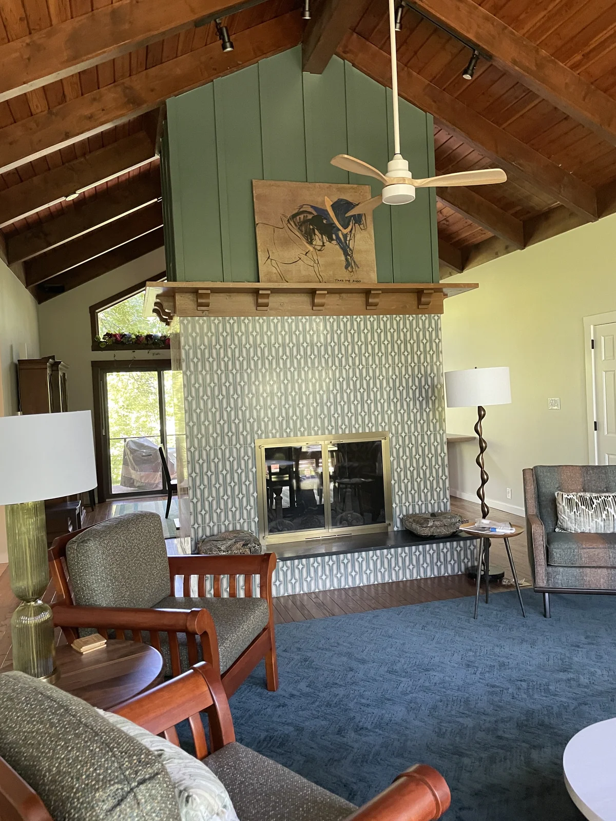 Patterned porcelain fireplace with a dark granite base in a living room with a timber ceiling.