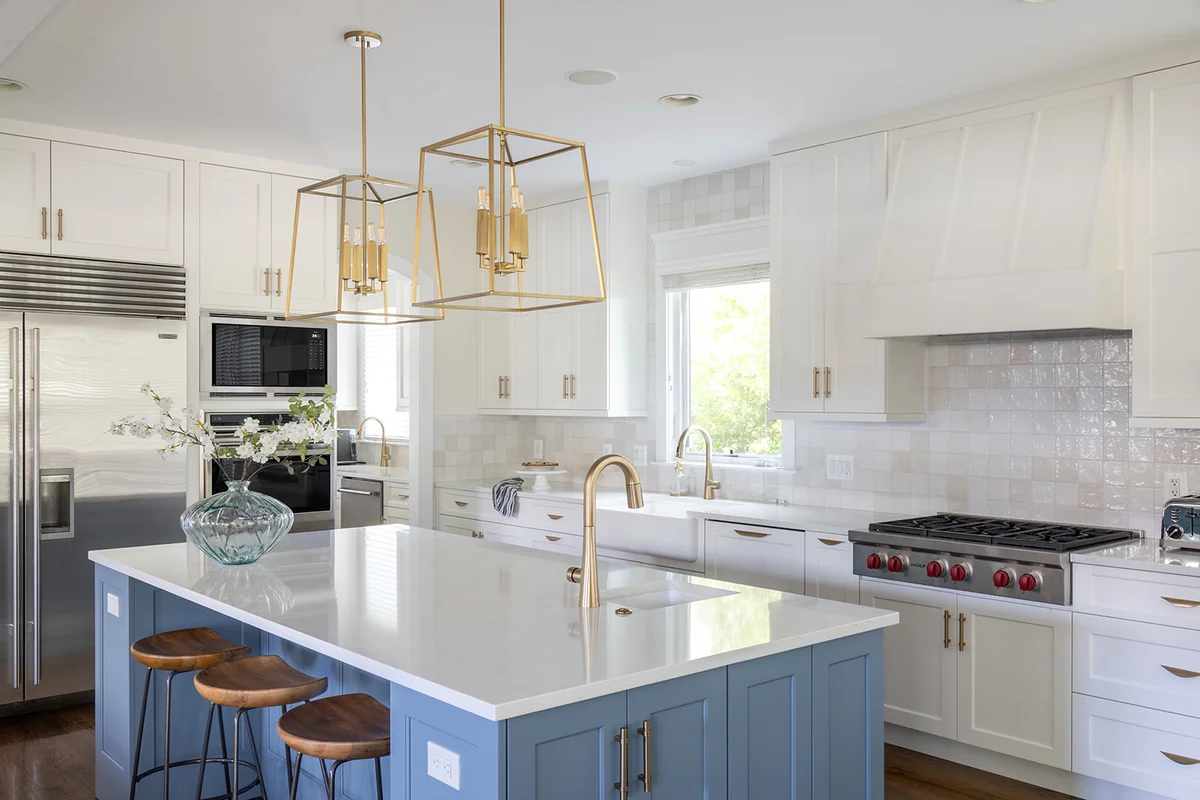 White kitchen with a blue island, light stone countertops and a glossy tile backsplash.